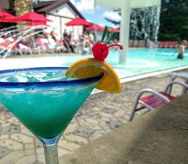 cabana bar blue cocktail drink with orange slice by poolside